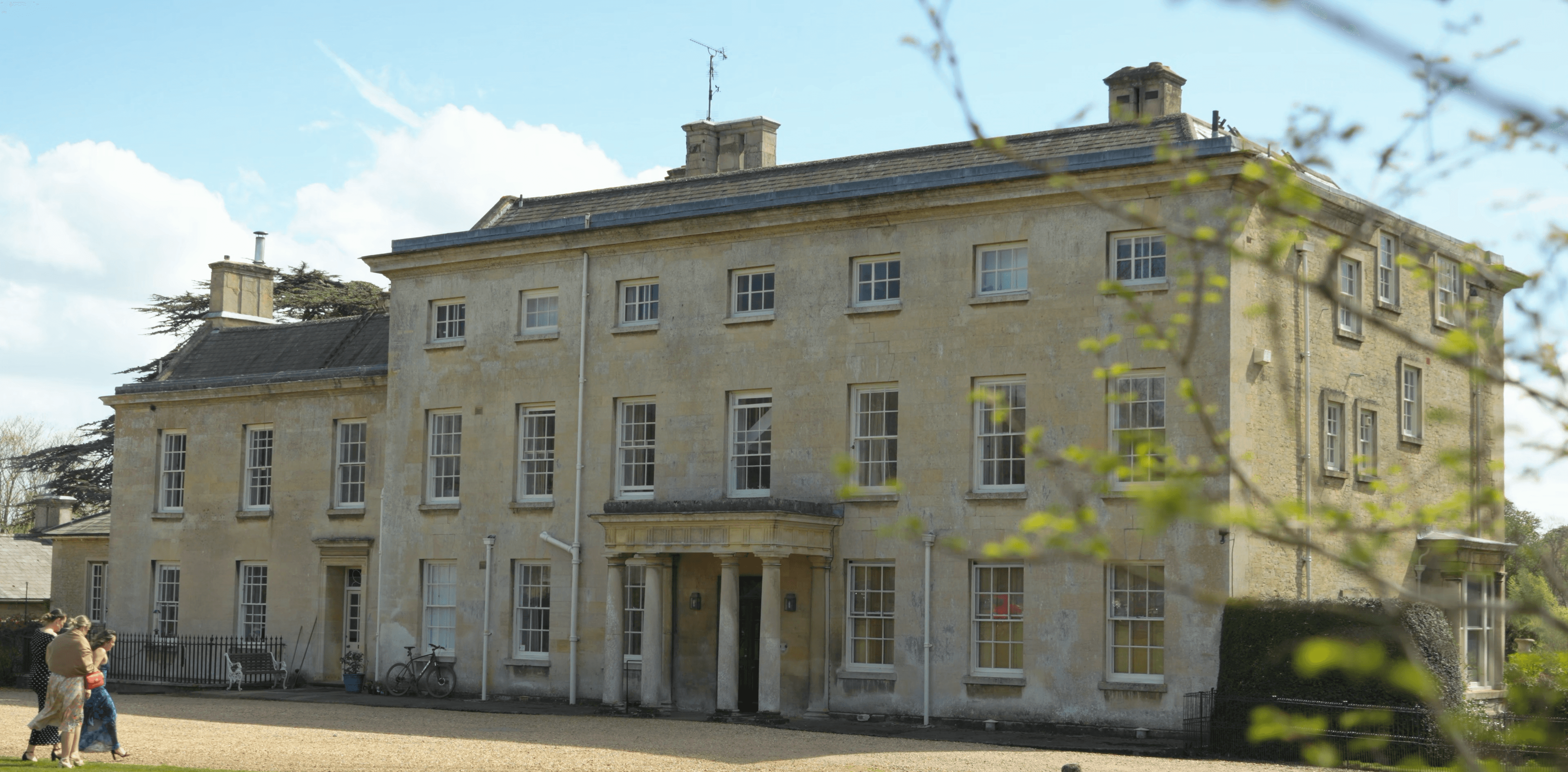 Historic Georgian-style stone estate building with a central columned portico and numerous sash windows.